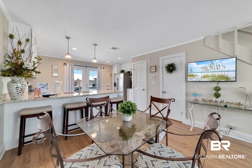 Dining area with a glass-top table, patterned chairs, and breakfast bar beside sliding glass doors.