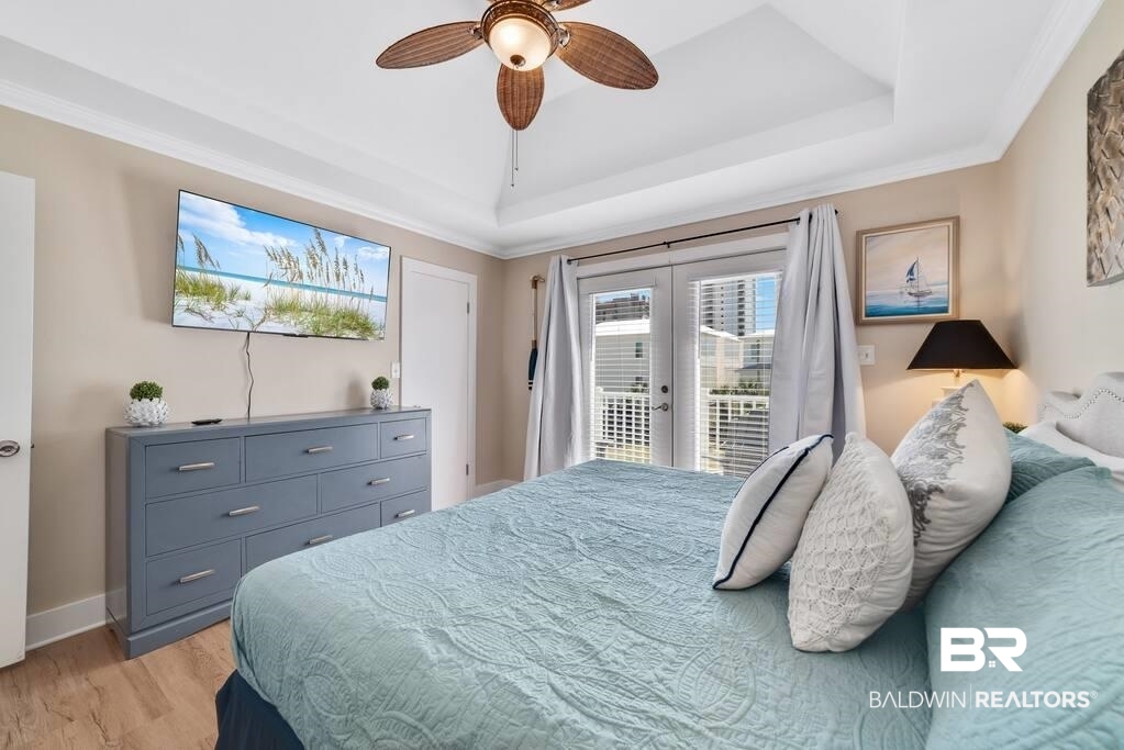 Bedroom with pale aqua bedding, a blue dresser, and French doors overlooking neighboring buildings.