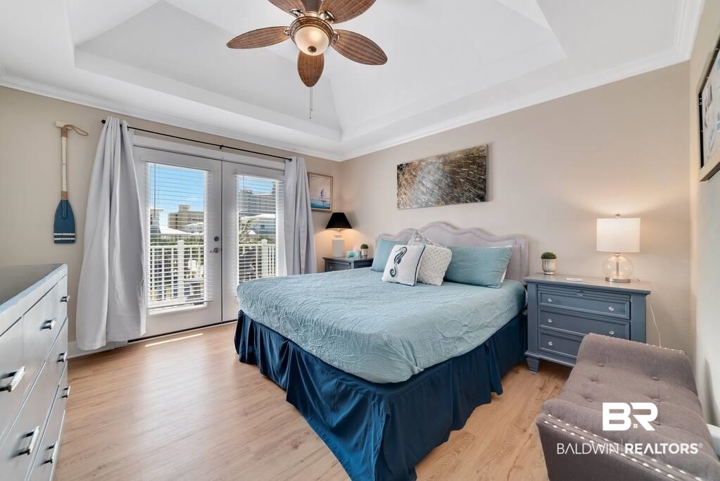 Bedroom with pale blue bedding, a wood-blade ceiling fan, and glass balcony doors.