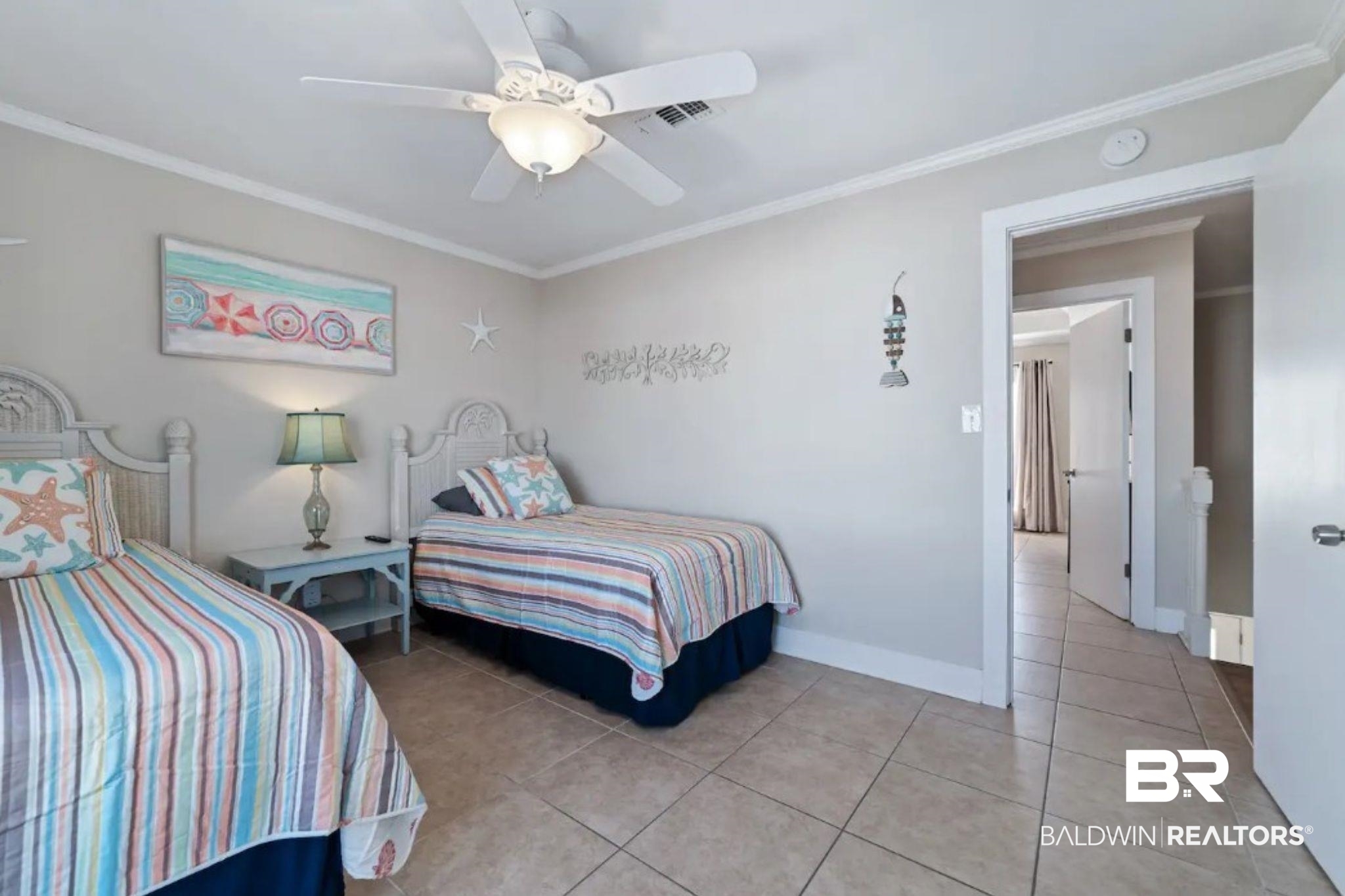 Bedroom with two twin beds in pastel striped bedding and coastal-themed pillows.