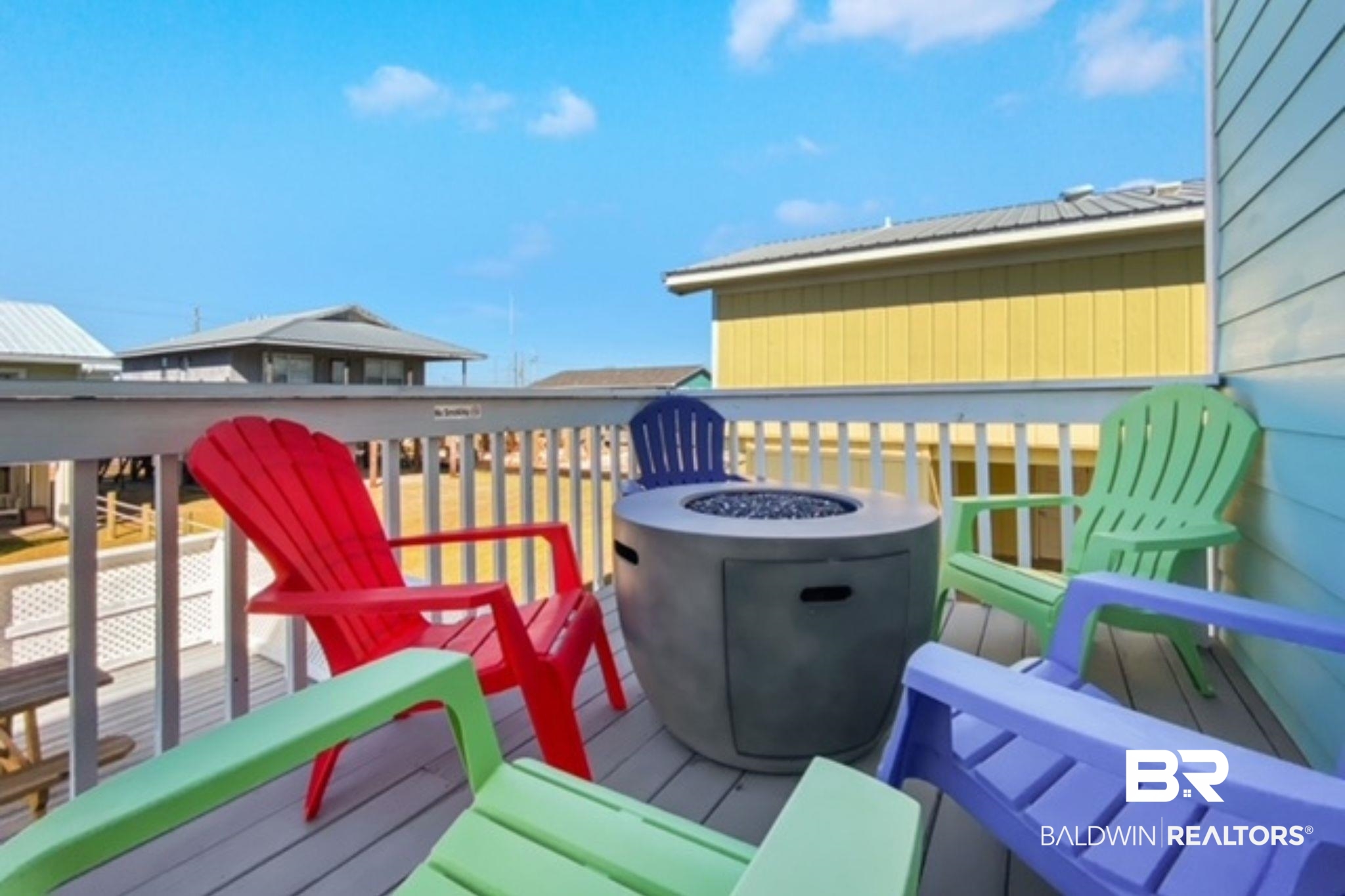 Deck with colorful Adirondack chairs surrounding a round fire pit.
