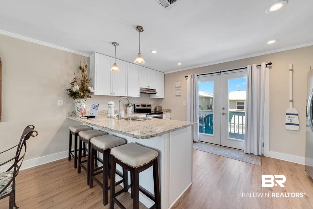 Kitchen with a granite island and four bar stools beside glass doors to a balcony.