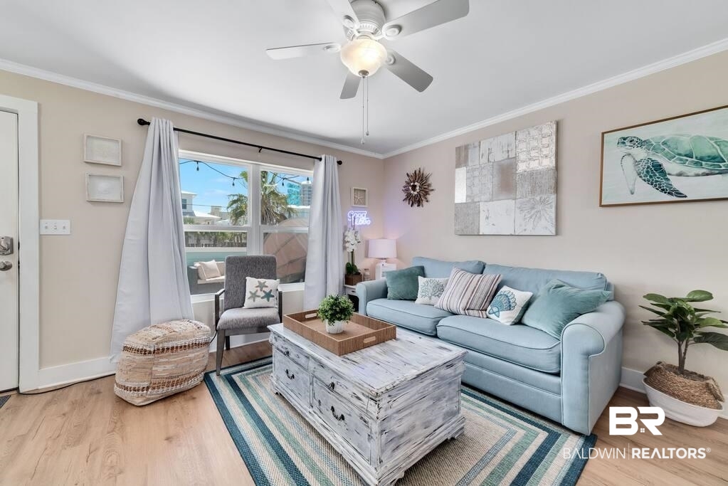 Living room with a light blue sofa, striped rug, and large window overlooking an outdoor seating area.