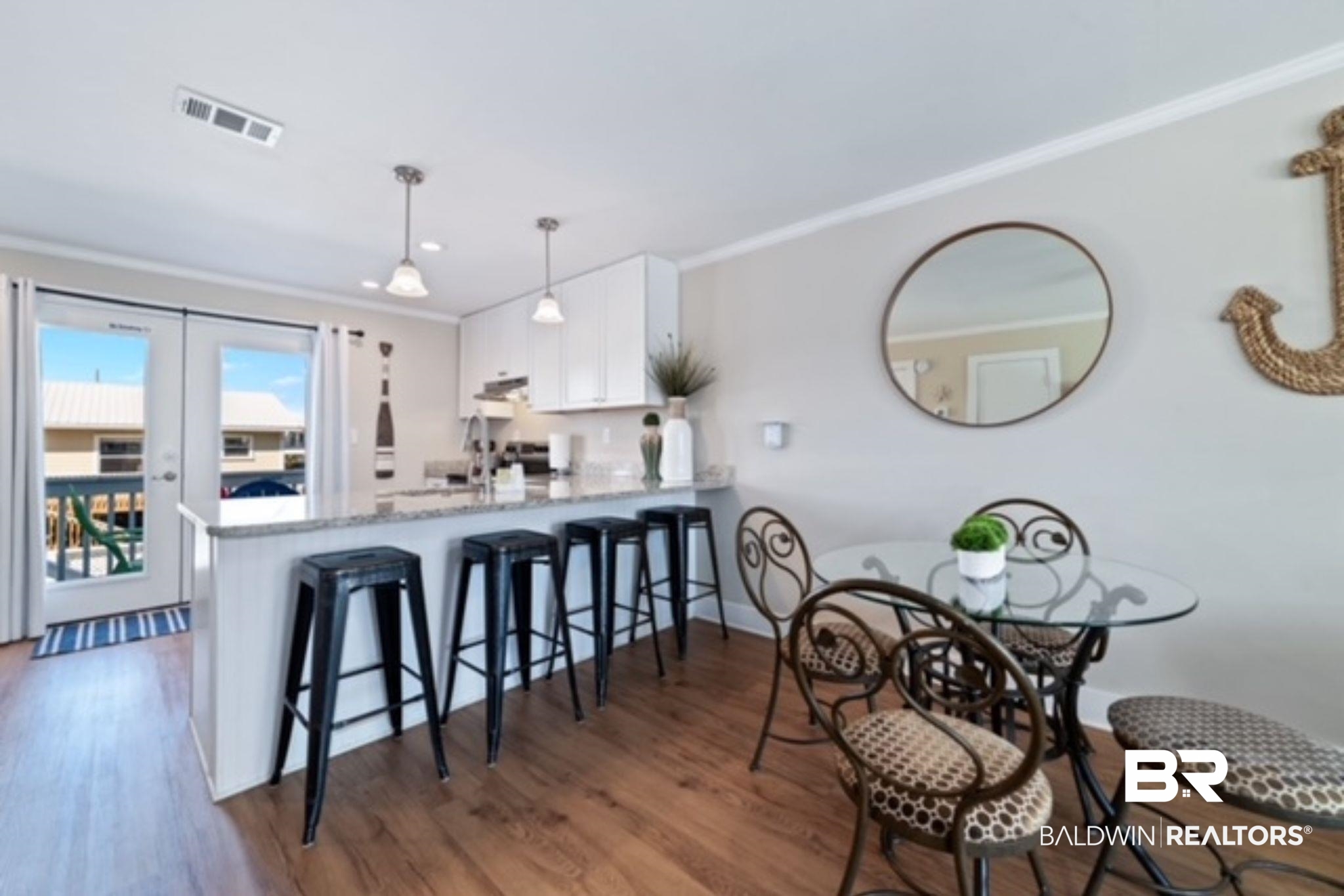 Kitchen and dining area with a stool-lined breakfast bar and glass door to a balcony.