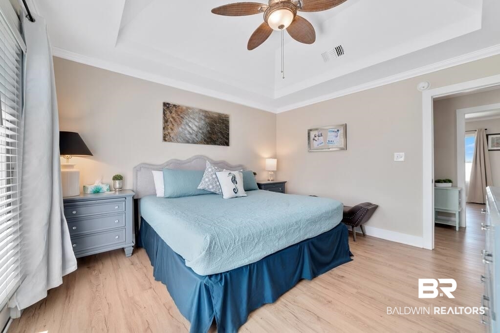 Furnished bedroom with a king bed, blue bedding, gray nightstands, and a wood ceiling fan.