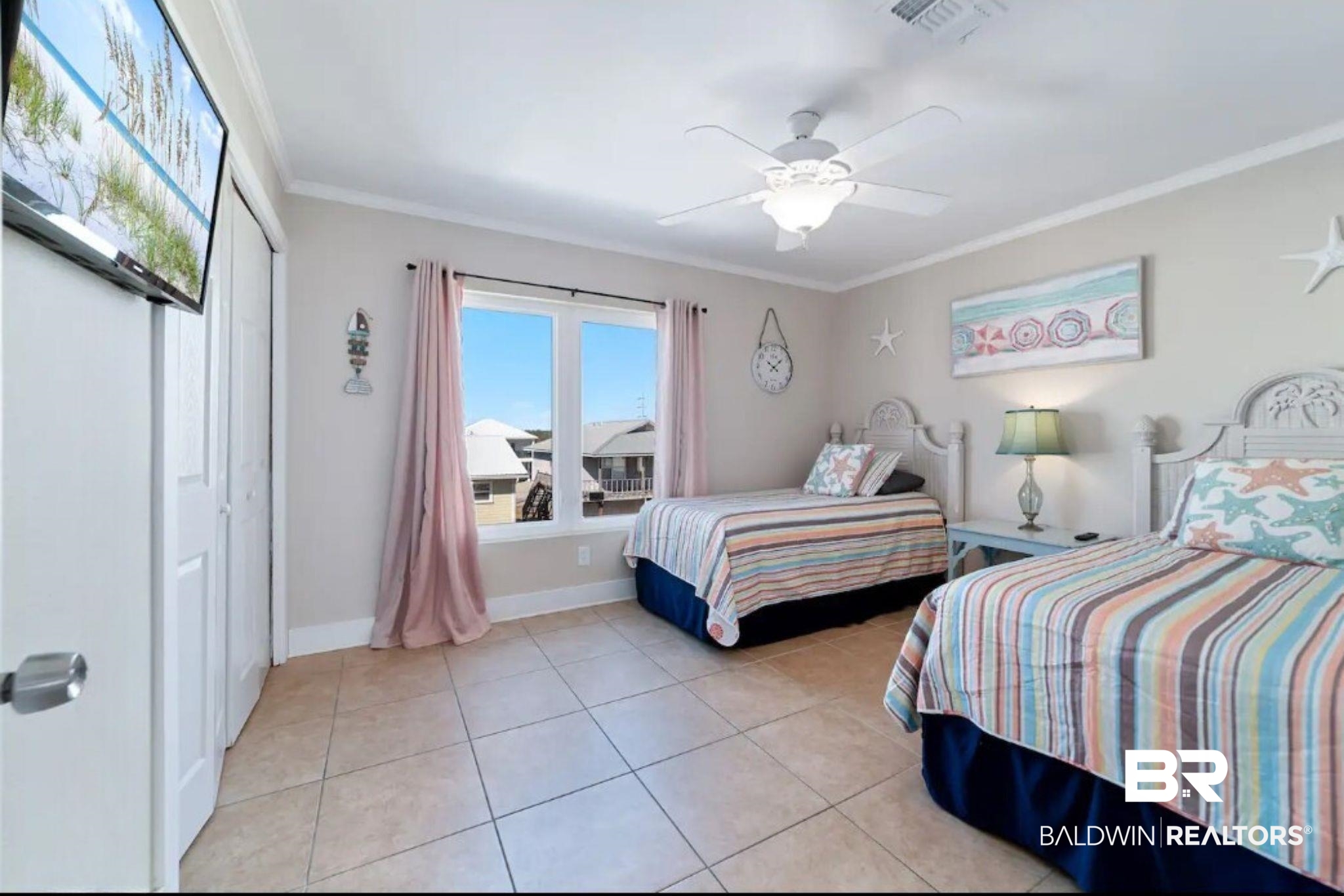 Bedroom with two twin beds in striped bedding, pink curtains, and tiled floors.