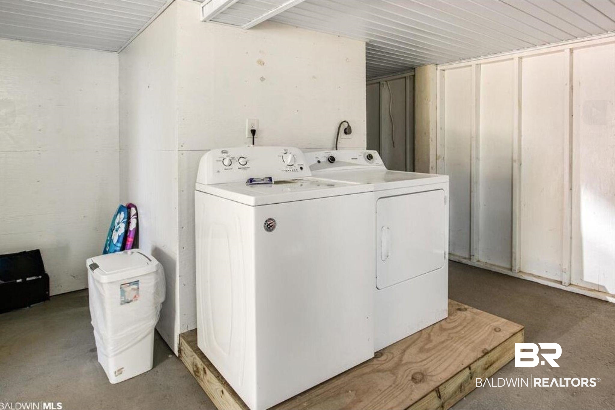 Laundry room with a washer and dryer raised on a wooden platform.