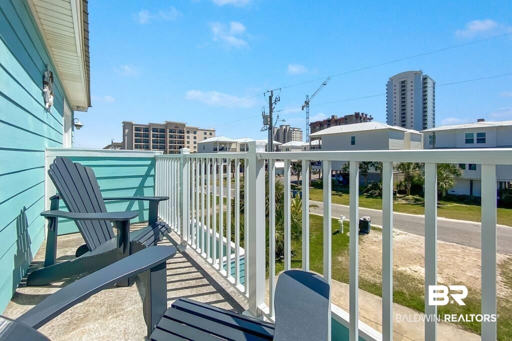 Turquoise balcony with Adirondack chairs overlooking nearby homes and a street.