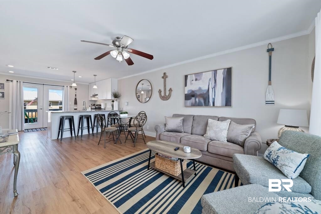 Open-plan living and dining room with a gray sofa, striped rug, and kitchen island.