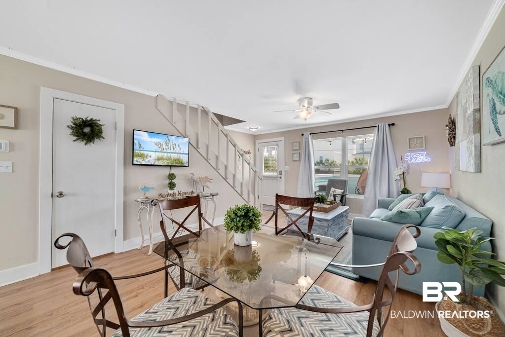 Open living and dining area with a glass table, pale blue sofa, staircase, and sliding glass doors.