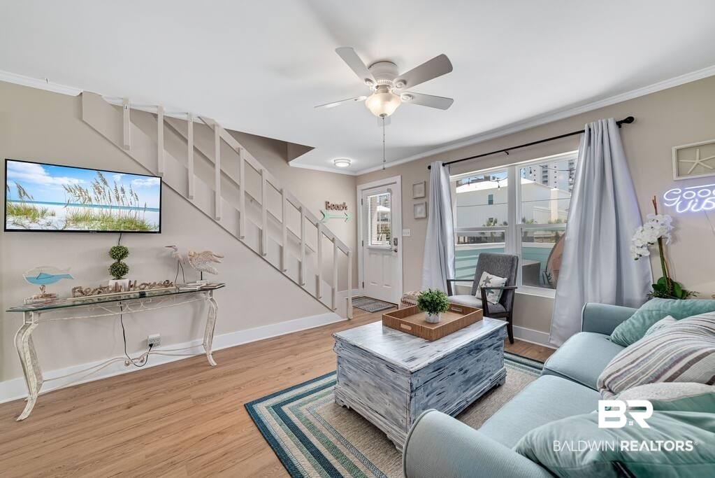 Living room with a light blue sofa, distressed wood coffee table, and staircase beside pool-facing glass doors.