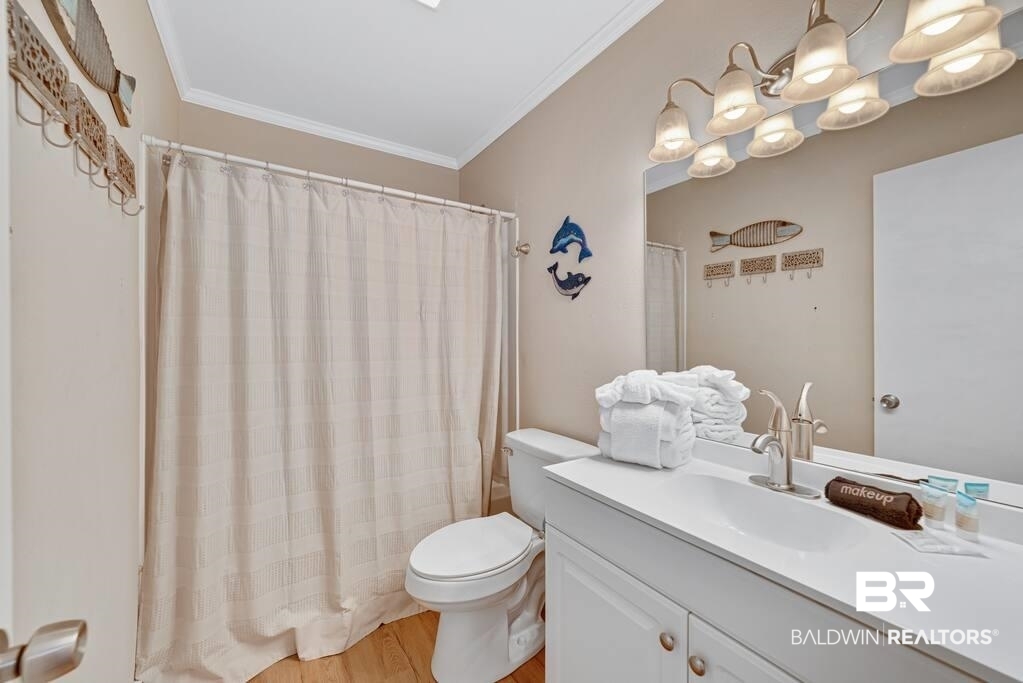 Bathroom with a white vanity, curtained shower, and coastal fish decorations.