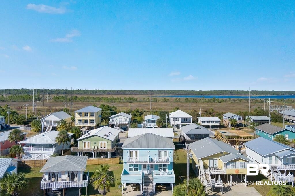Aerial view of raised coastal homes with water visible beyond the neighborhood.