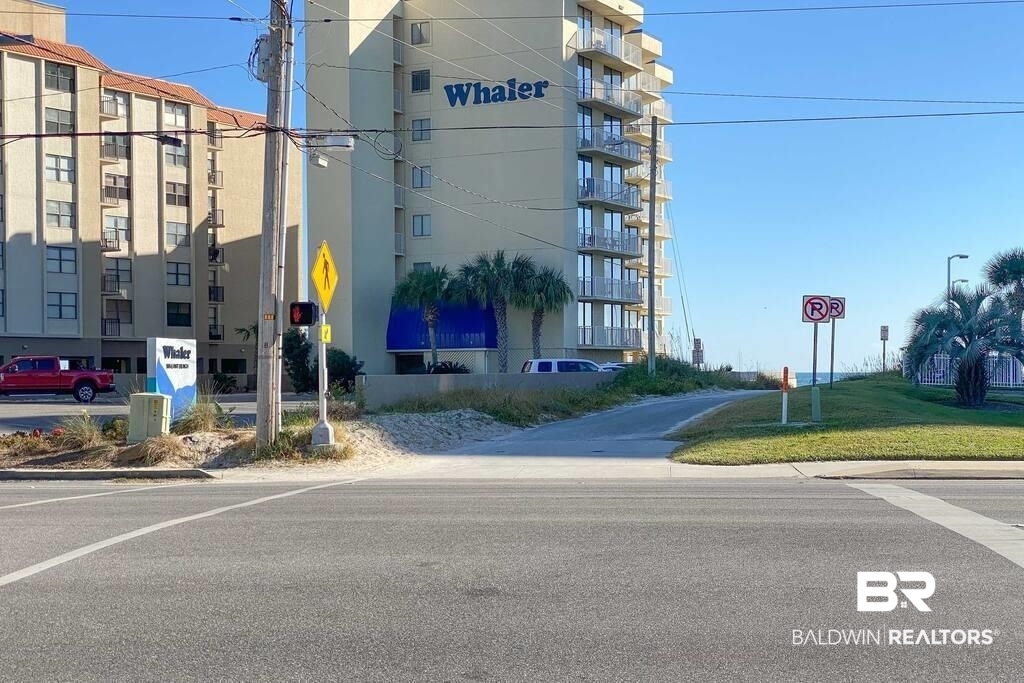 The Whaler condominium beside a beach access path, with the Gulf visible beyond.