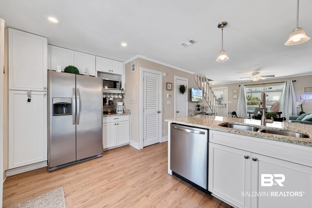 Kitchen with white cabinets, stainless steel appliances, and a granite-topped island opening to the living area.