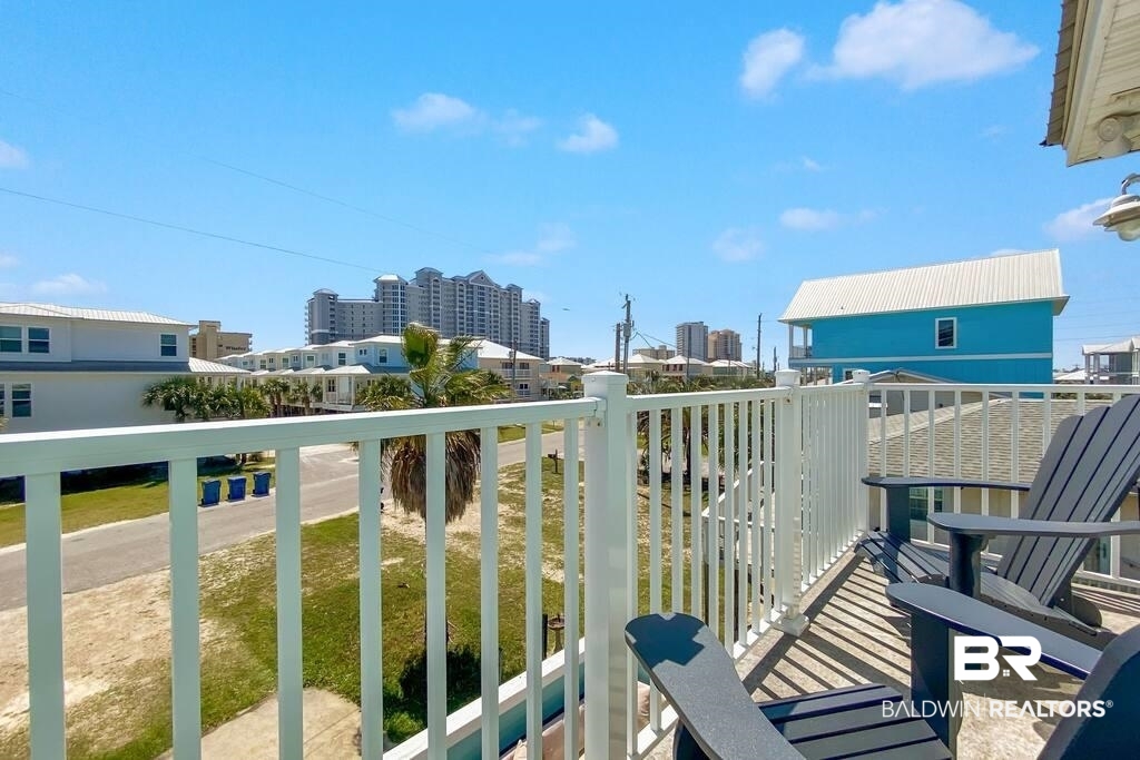 Balcony with white railings and chairs overlooking nearby homes and high-rise buildings.