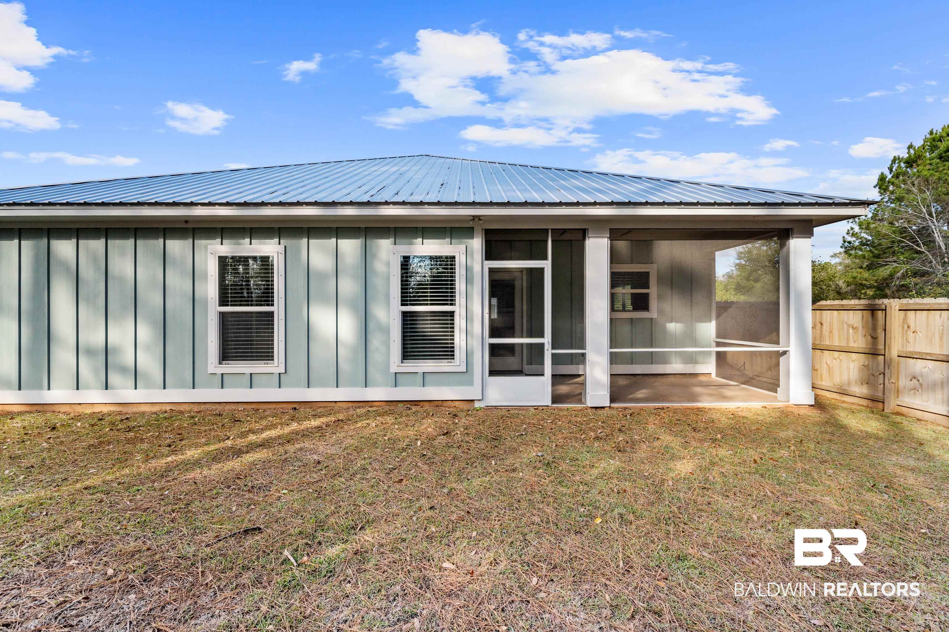 Rear of a light blue home with a metal roof and screened porch.