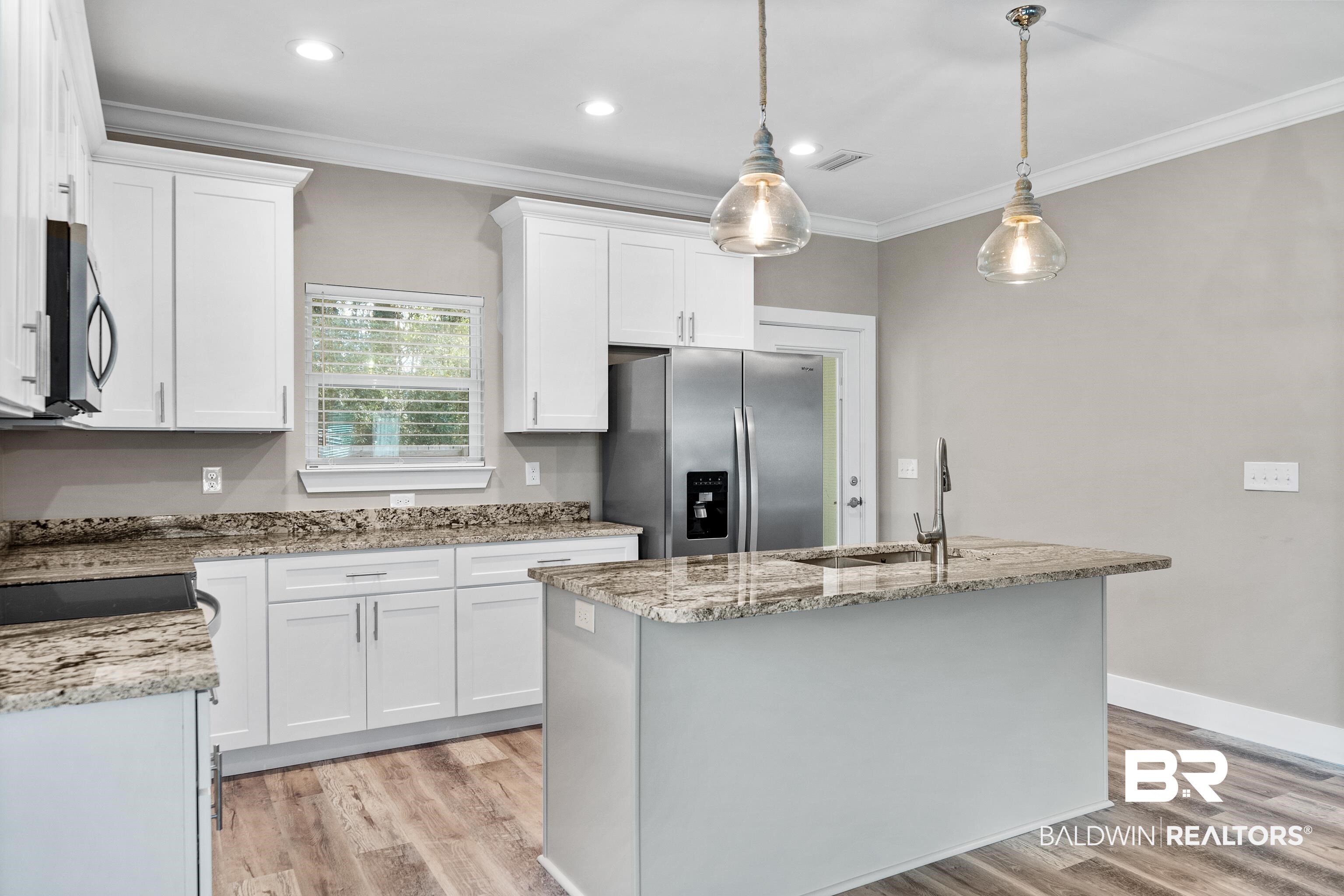 Modern kitchen with white cabinets, granite counters, stainless steel appliances, and a large island.