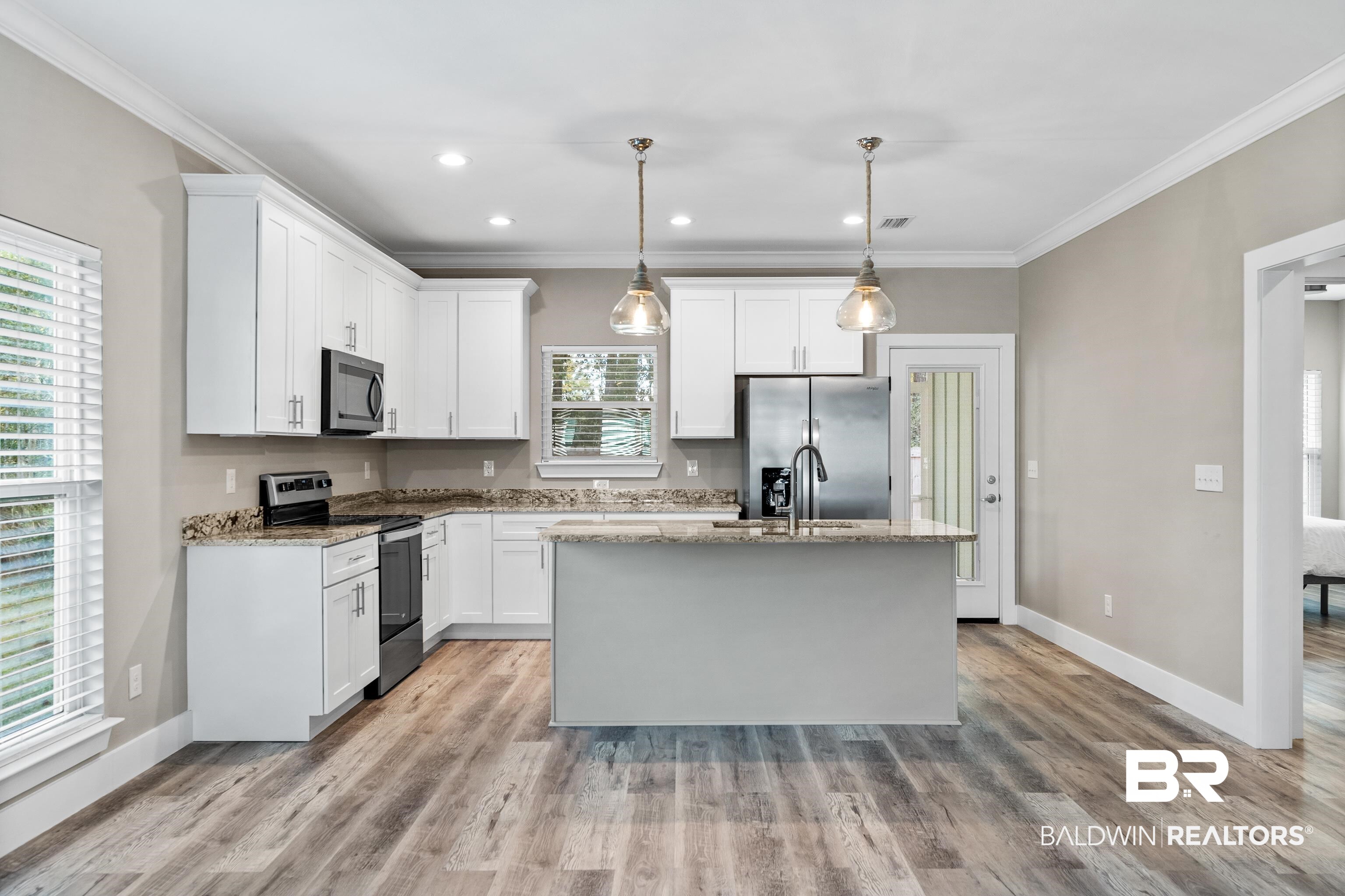 Kitchen with white cabinets, stainless steel appliances, granite counters, and a large central island.