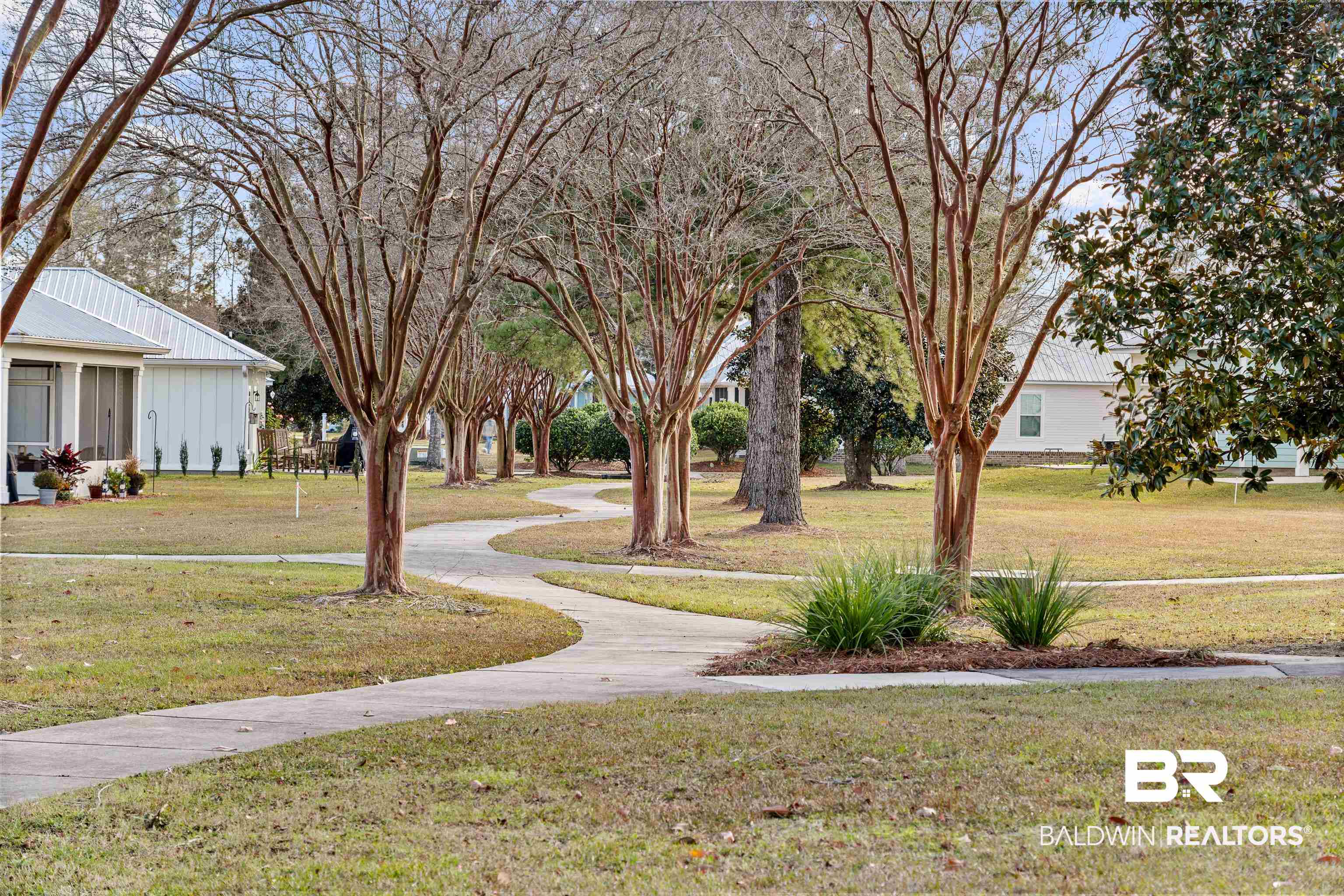 Landscaped grounds with winding sidewalks and mature trees between light-colored homes.