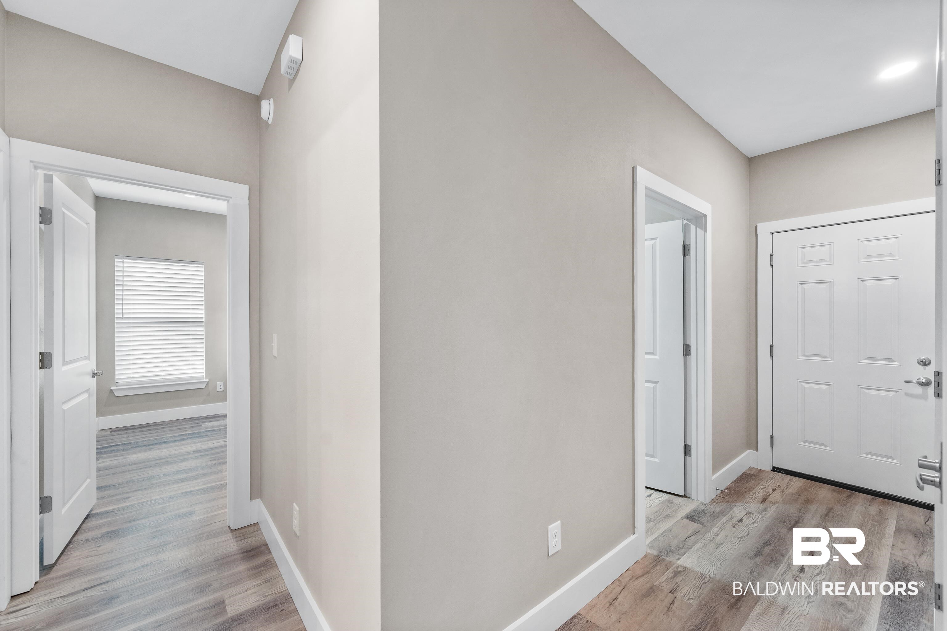 Unfurnished entryway with a white front door, beige walls, and plank flooring.