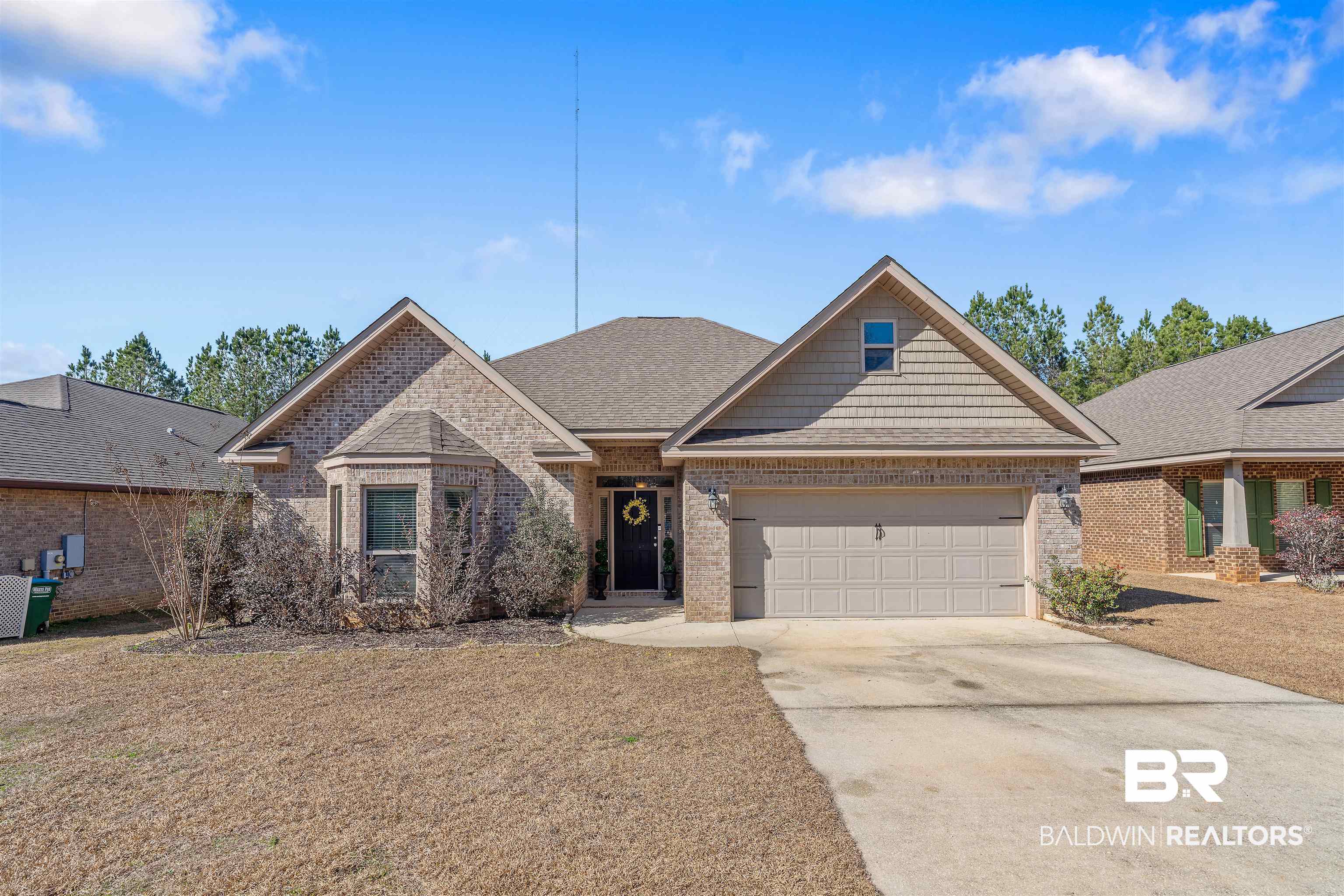 Brick house with gabled roofs, a two-car garage, and a concrete driveway.
