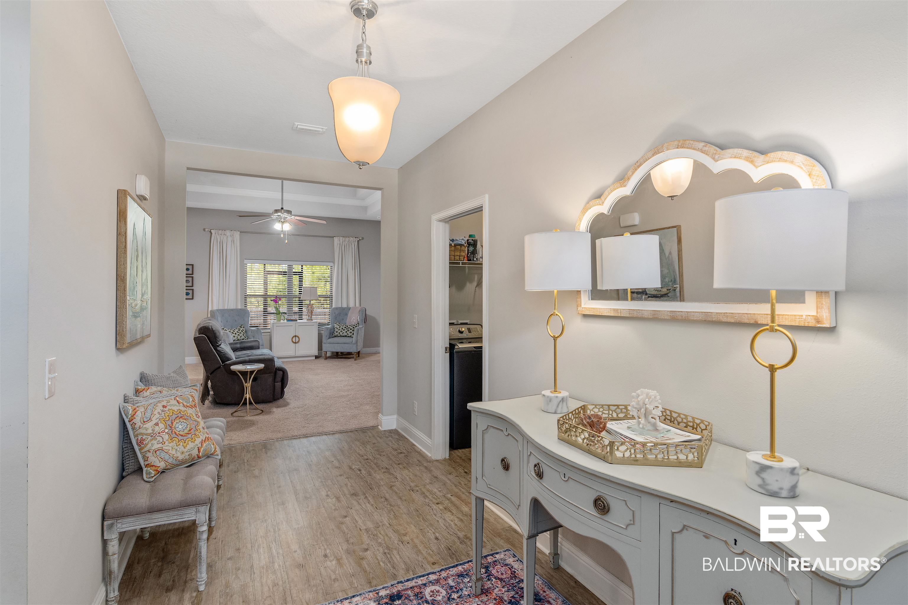 Furnished entry hall with a gray console and mirror, bench, and view into the living room.