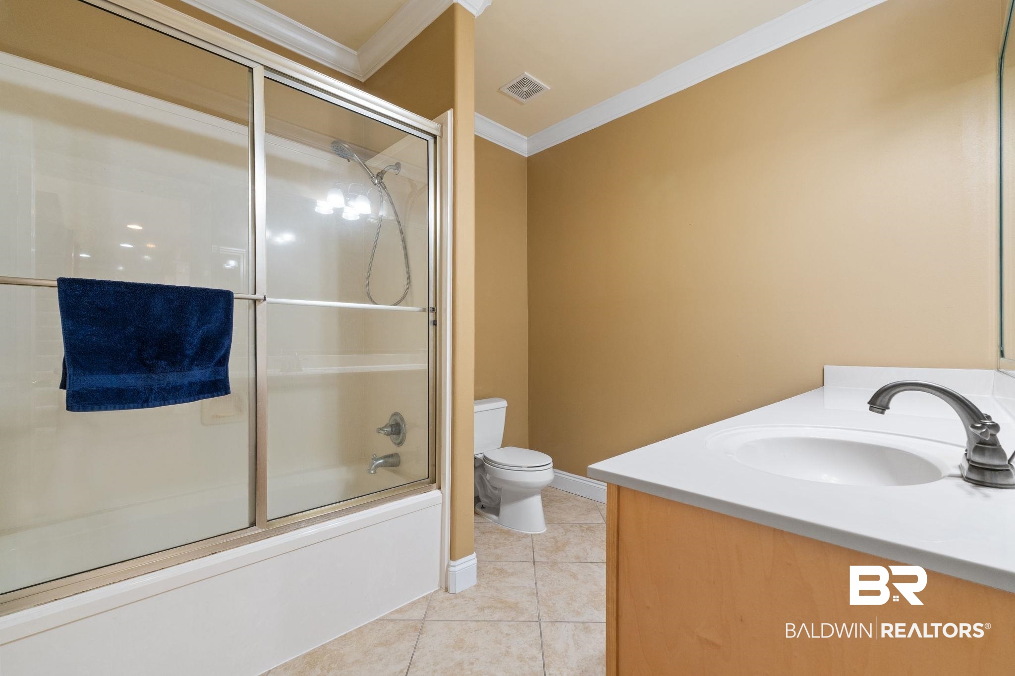 Bathroom with glass-enclosed shower, navy towel, toilet, and white vanity.