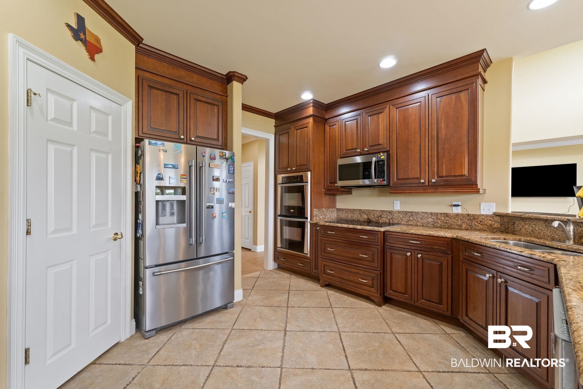 Kitchen with dark wood cabinets, granite counters, stainless steel appliances, and a double oven.