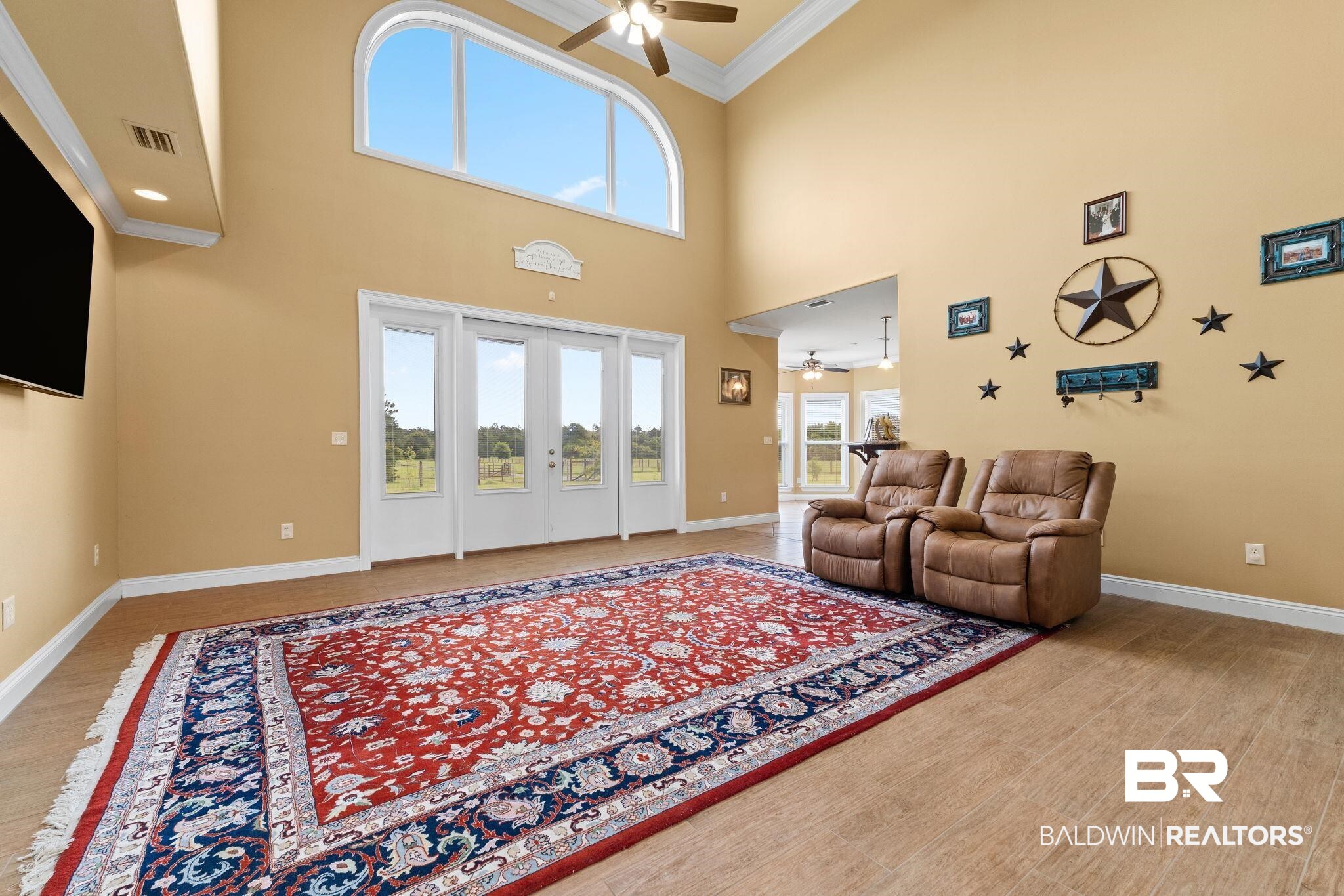 Living room with leather recliners, a large patterned rug, and glass doors overlooking a fenced yard.