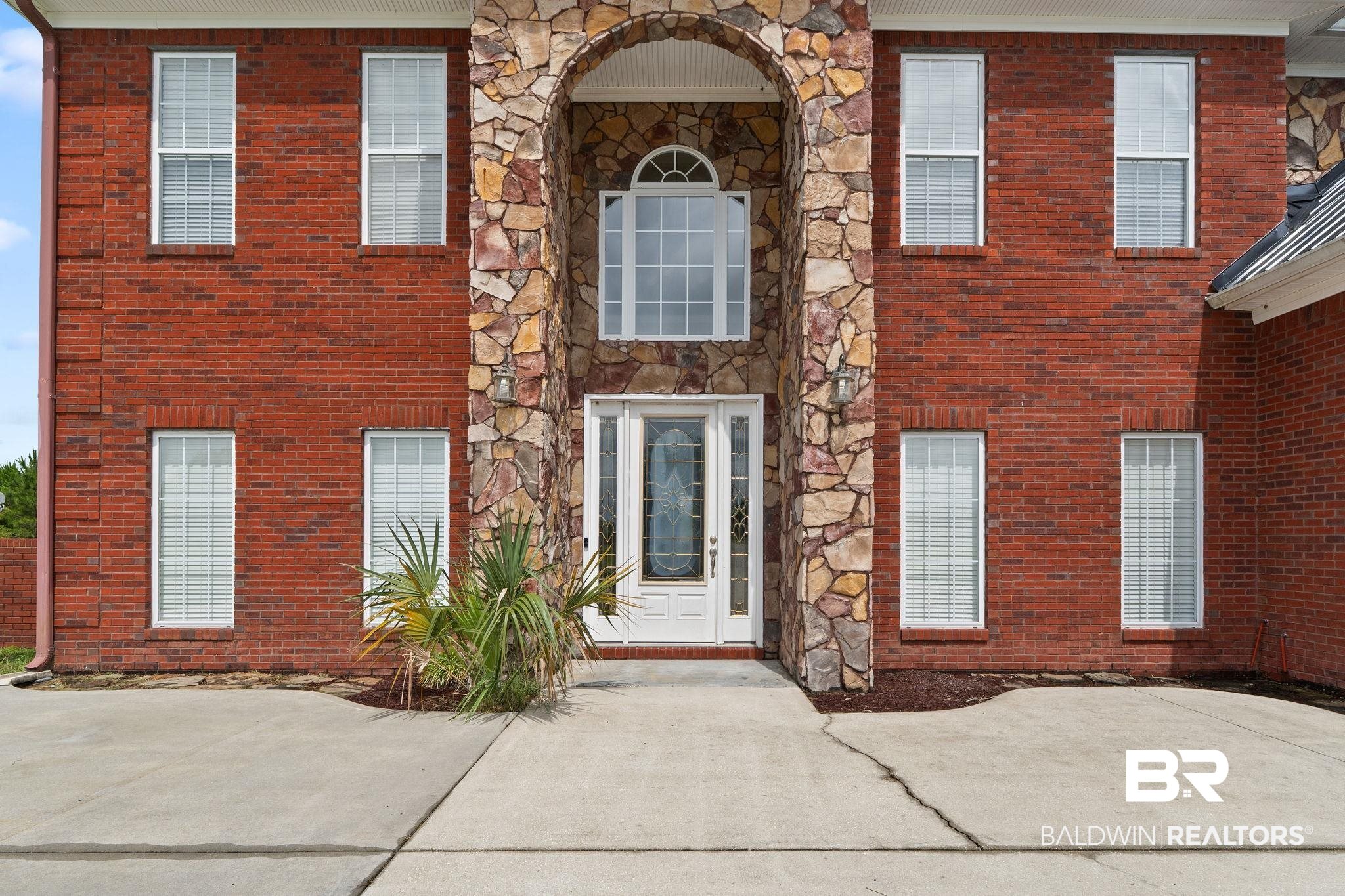 Two-story red-brick house with a large stone arch around its front entrance.