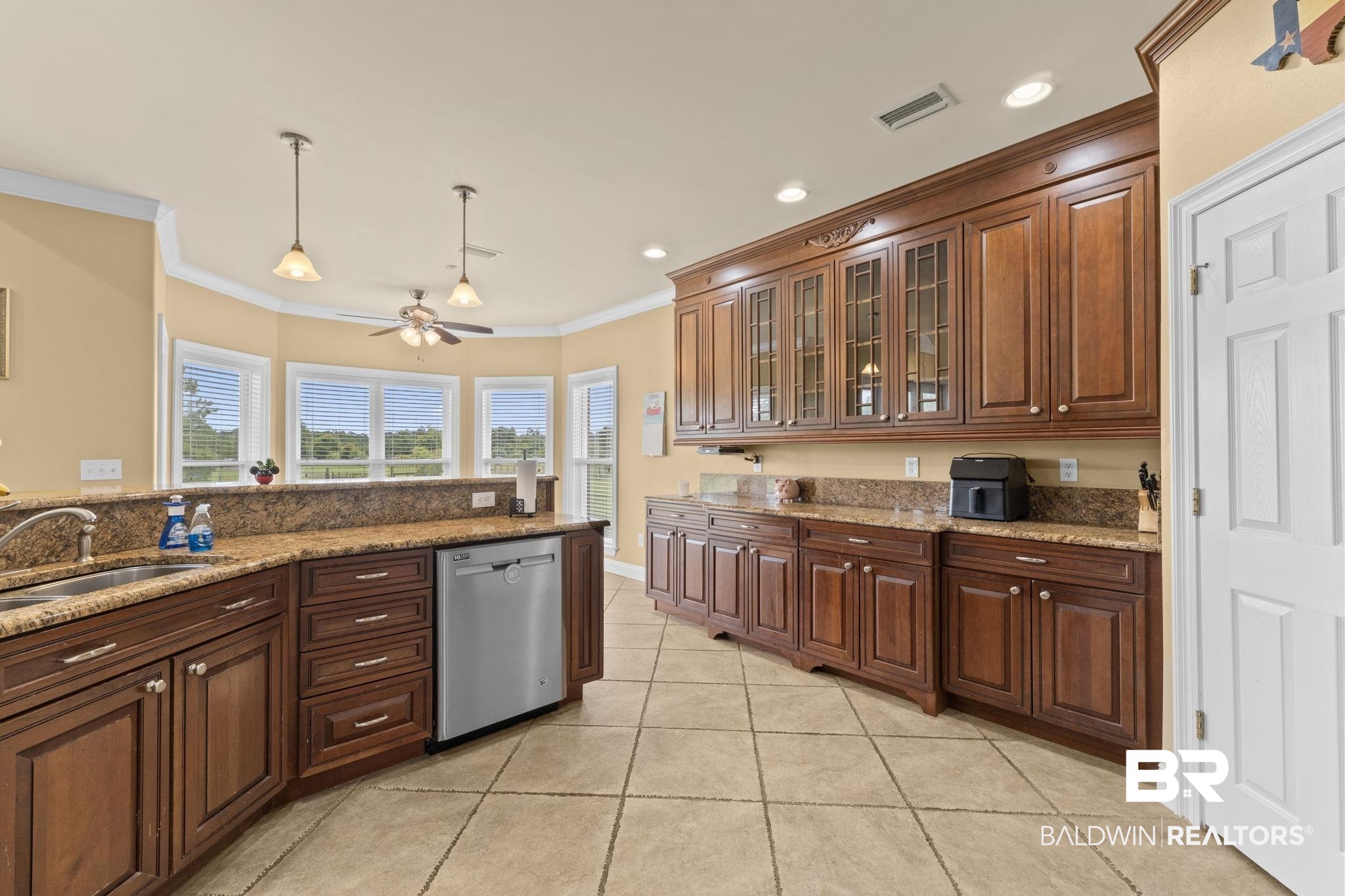 Kitchen with dark wood cabinetry, granite counters, and large windows with white blinds.