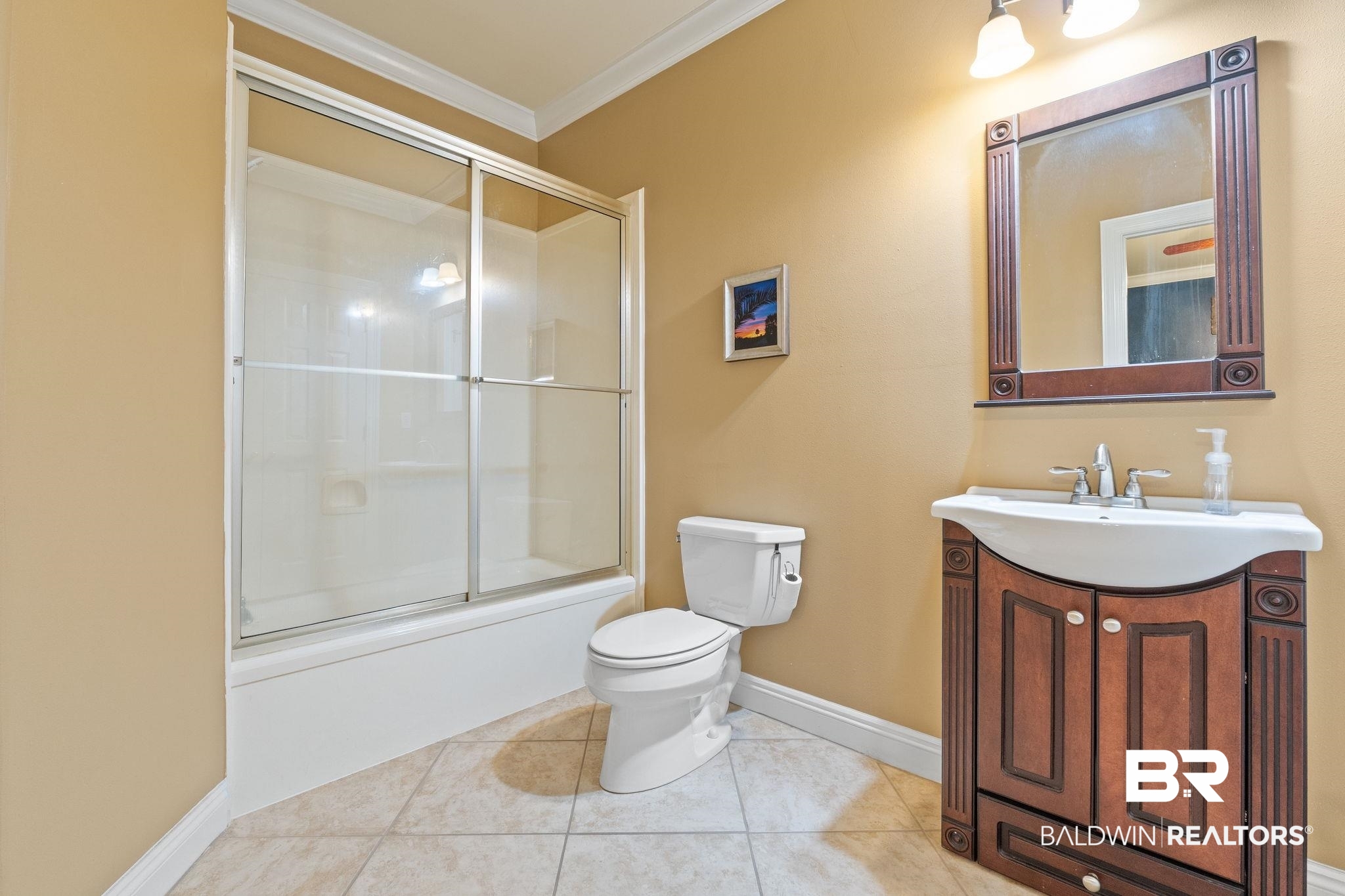 Bathroom with a glass-enclosed tub and shower beside an ornate dark wood vanity.