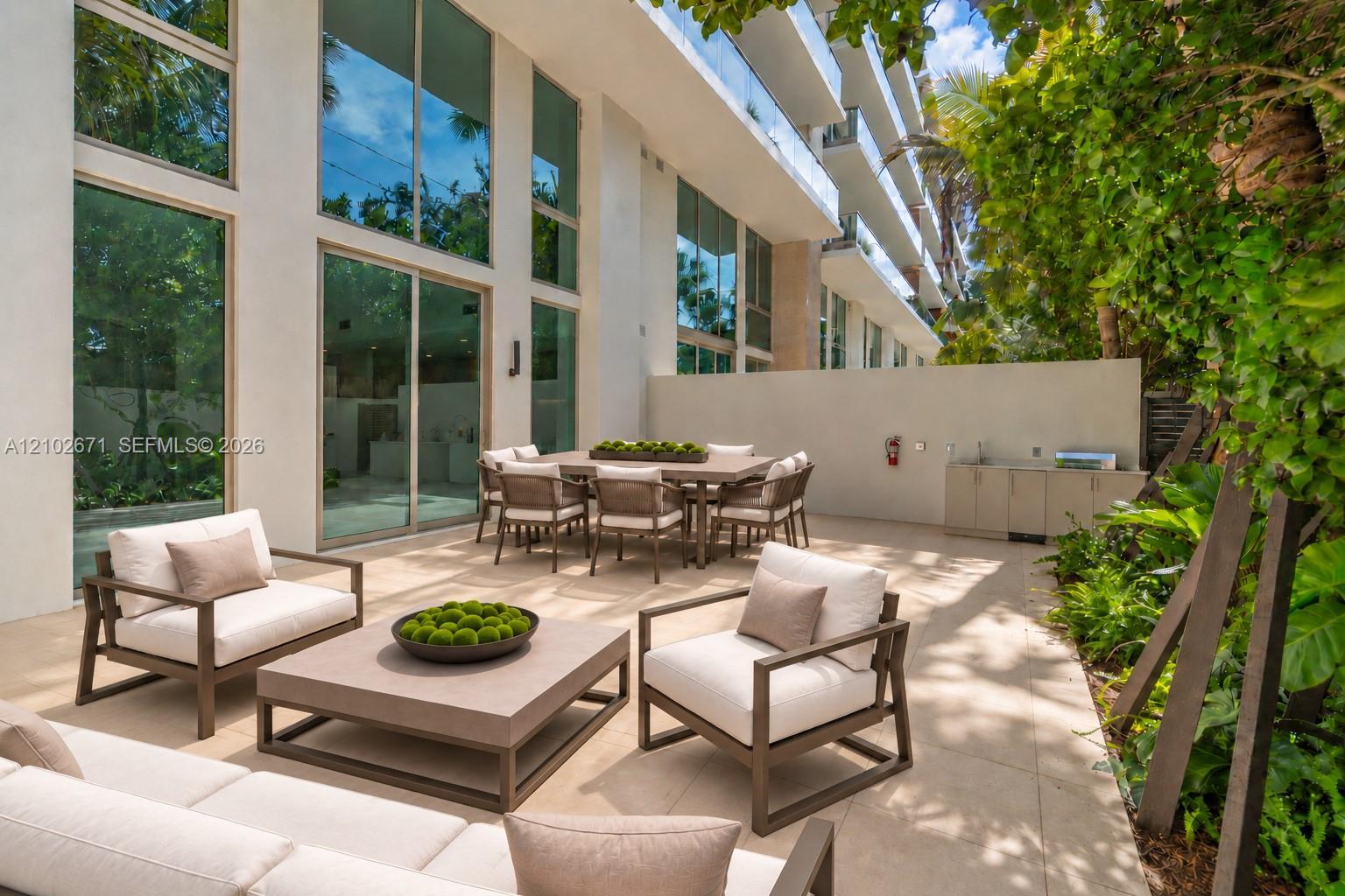 Modern residential courtyard patio with lounge seating, outdoor dining, and tropical greenery.