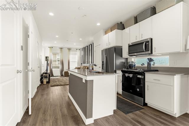 Open-plan kitchen with a large island, white cabinets, and stainless steel appliances.