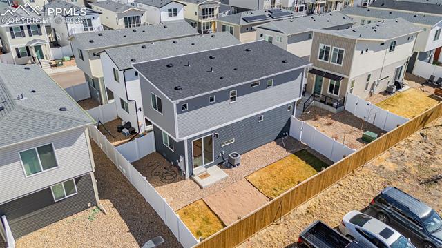 Aerial view of a gray two-story home with a fenced, mostly bare backyard.