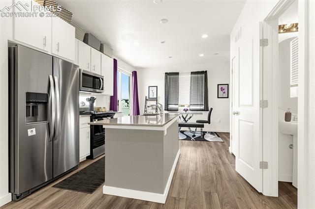 White kitchen with stainless steel appliances, a large island, and an adjoining dining area.