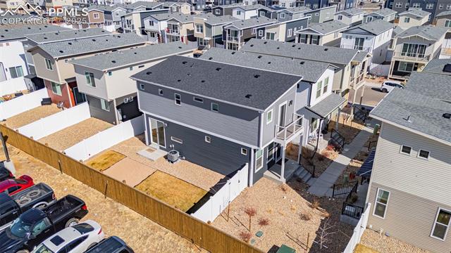 Aerial view of a gray two-story home with a fenced backyard and closely spaced neighboring houses.