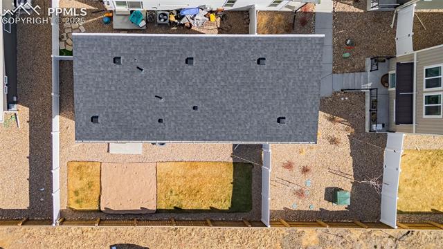 Aerial view of a house with a large gray roof and fenced backyard.