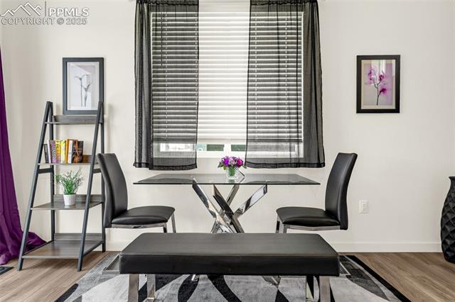 Dining area with a glass-top table, two black chairs, and a bench on a geometric rug.