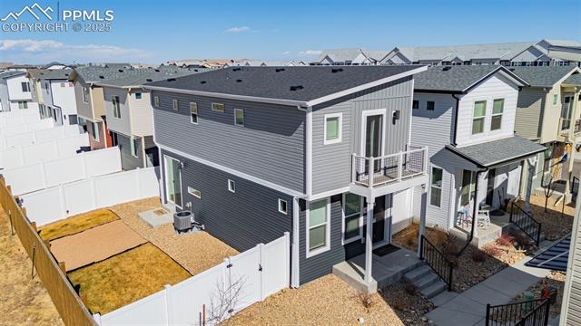 Two-story gray home with a small balcony and fenced yard, viewed from above.