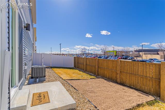 Fenced backyard with a concrete patio, gravel landscaping, and an outdoor air-conditioning unit.