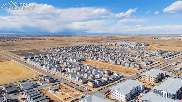 Aerial view of a residential neighborhood with distant mountains and open land.