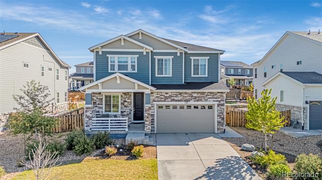Two-story blue house with stone accents, a covered porch, and a two-car garage.