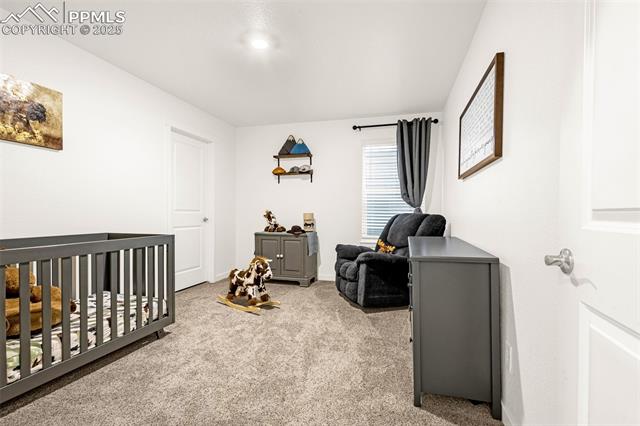 Nursery with a gray crib, matching dresser, and upholstered rocking chair.