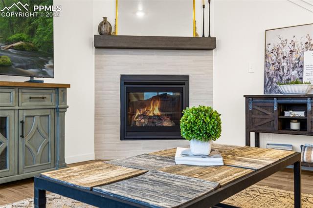 Living room with a black fireplace, rustic wood coffee table, potted plant, and distressed cabinetry.