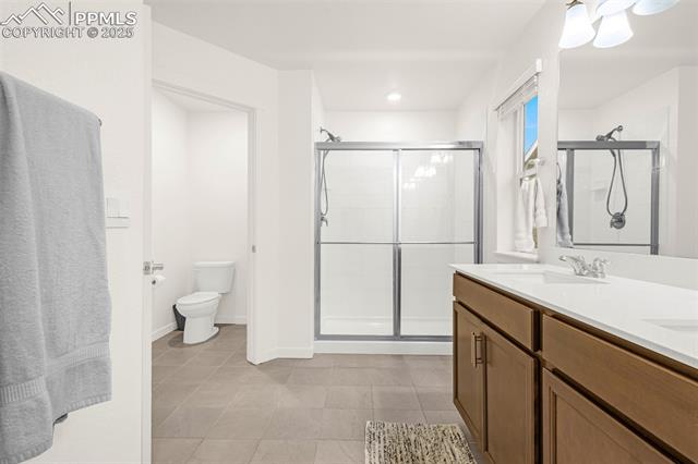 Bathroom with a glass shower, wood vanity, and gray tile floor.