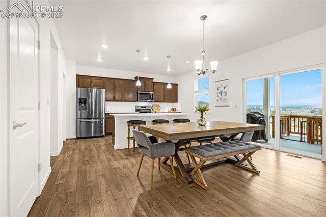 Open-plan kitchen and dining area with dark cabinets, a large table, and sliding doors to a balcony.
