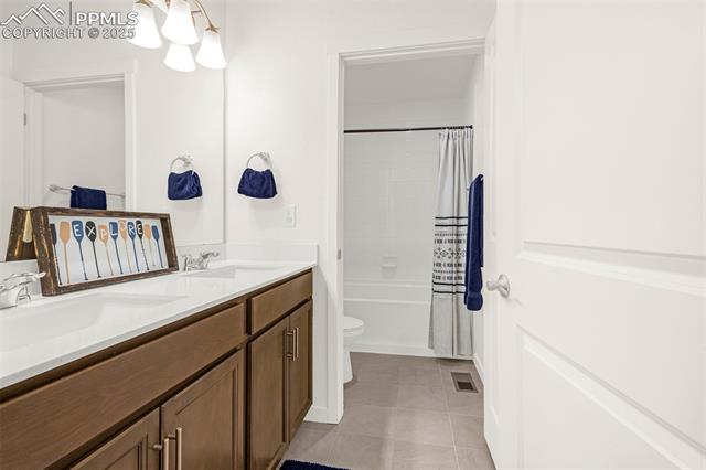 Bathroom with a long double vanity and dark wood cabinets beside a tub with a striped shower curtain.
