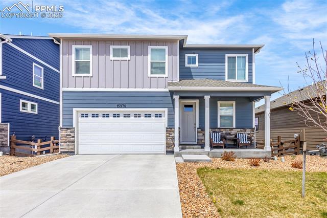 Two-story blue and gray house with a wide driveway, white garage door, and covered porch.